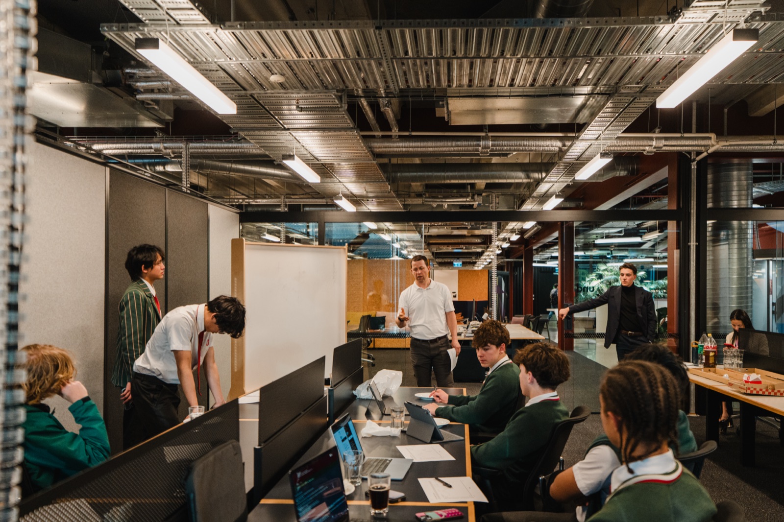 A session in full swing at the B:HIVE: students working while a mentor talks them through the whiteboard